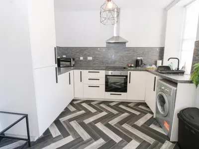 a kitchen with white cabinets and a geometric floor at Lowther Apartment in Whitehaven