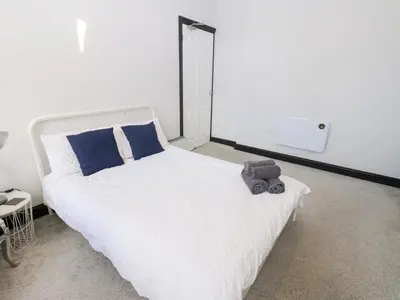 a bedroom with a white bed with a teddy bear on it at Lowther Apartment in Whitehaven