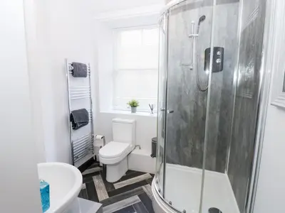 a bathroom with a shower and a toilet and a sink at Lowther Apartment in Whitehaven