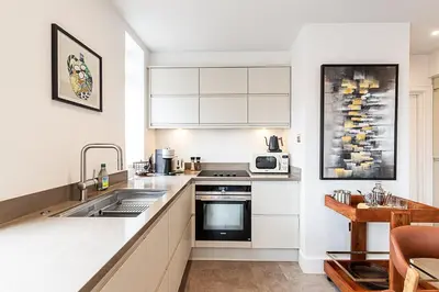 a kitchen with white cabinets and a sink at Stylish Chelsea Flat Near Sloane Square in Moffat