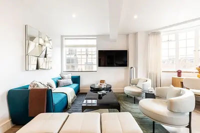 a living room with a blue couch and chairs at Stylish Chelsea Flat Near Sloane Square in Moffat
