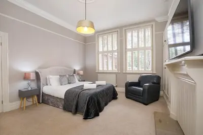 a bedroom with a bed and a chair at 2 On The Green in Moffat