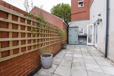 a brick fence with a plant in a pot next to a sidewalk at 2 On The Green in Moffat