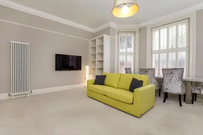 a living room with a yellow couch and a table at 2 On The Green in Moffat