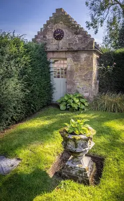 a stone building with a white door with a clock at Spedlins Castle in Templand