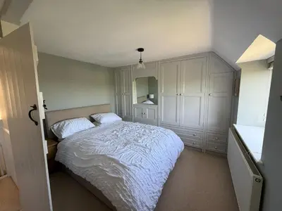 a bedroom with a white bed and a cabinet at Cosy Cottage in Cotswolds in Moffat