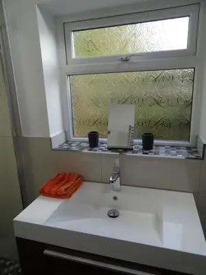 a window above a white sink with two cups on it at Lazy Lodge in Foxdale