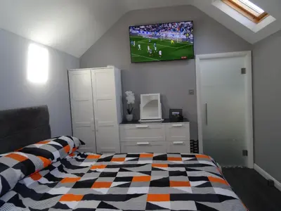 a bedroom with a bed and a tv on the wall at Lazy Lodge in Foxdale