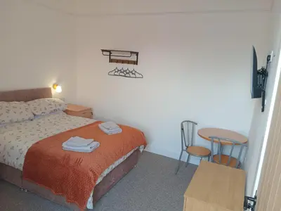 a small bedroom with a bed and a table at Double Ensuite - City centre homestay - Peterill Room - in Carlisle