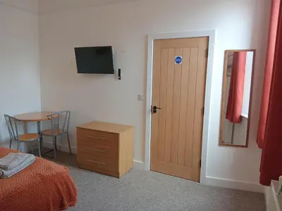 a bedroom with a door and a table with a chair at Double Ensuite - City centre homestay - Peterill Room - in Carlisle