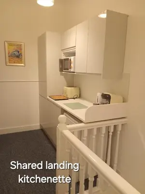 a small kitchen with white cabinets and a counter at Double Ensuite - City centre homestay - Peterill Room - in Carlisle