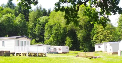 a group of mobile homes in a field with trees at Moffat Manor Holiday Resort in Beattock