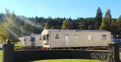 a tiny house is parked next to a train at Moffat Manor Holiday Resort in Beattock