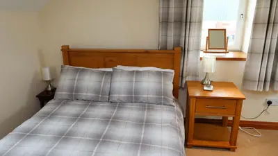 a bedroom with a bed and a table with a mirror at Wee Newton in Twynholm
