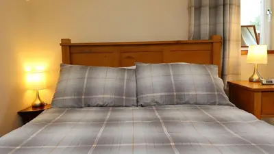 a bed with two lamps and two pillows on it at Wee Newton in Twynholm