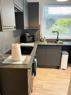a kitchen with black cabinets and a counter top at The Retreat, Cosy 1 Bed Cottage, Town Centre Location in Kirkcudbright