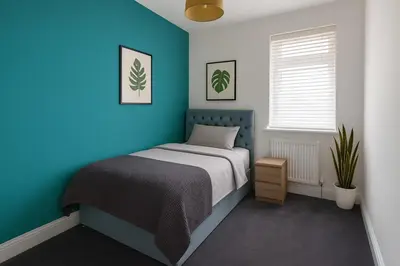 a bedroom with a bed with a blue wall at Coastal Haven - Steps From Beach in Whitehaven