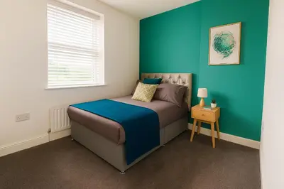 a bedroom with a bed with a blue wall at Coastal Haven - Steps From Beach in Whitehaven