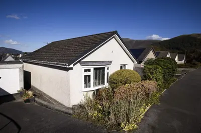 a white house with a black roof on a street at Skiddaw Heights in Keswick