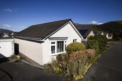 a white house with a black roof on a street at Skiddaw Heights in Keswick