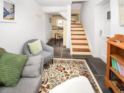a living room with a couch and a staircase at Hideaway Cottage in Keswick