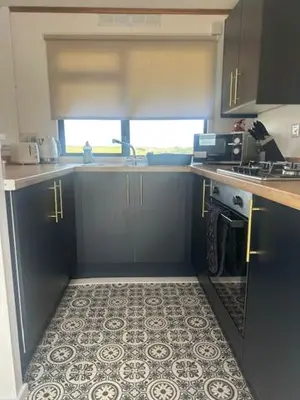 a kitchen with blue cabinets and a tile floor at Bowmore 7 - Stunning Sea Views, Farm Stay in Stranraer