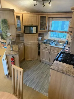 a kitchen with wooden cabinets and a stove top oven at The West Lakes Caravan in Lamplugh
