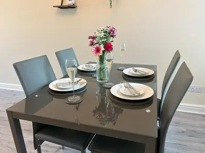 a dining room table with chairs and a vase of flowers at Birks Terrace - 2 Bedroom - Sleeps 4 in Cleator Moor