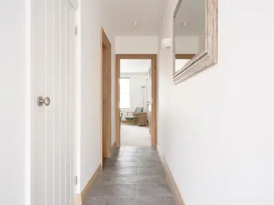 a hallway with white walls and a mirror on the wall at Richmond, Tithebarn St, Keswick in Keswick