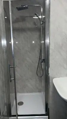 a shower with a glass door next to a sink at QueensBerry accommodation in Annan