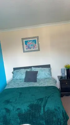 a bedroom with a bed with a green comforter at QueensBerry accommodation in Annan