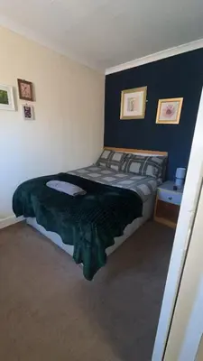 a bedroom with a bed with a green blanket at QueensBerry accommodation in Annan