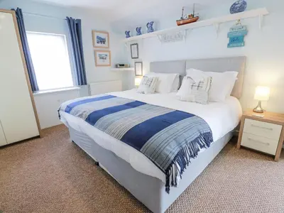 a bedroom with a large bed with white and blue sheets at Learig Lodge in Girvan