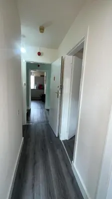 an empty hallway of an apartment with white walls and wood floors at QueensBerry accommodation in Annan