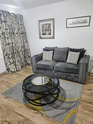a living room with a black couch and a glass table at Egremont 2-Bed Flat Near Lake District with Free Parking & Wi-Fi in Egremont