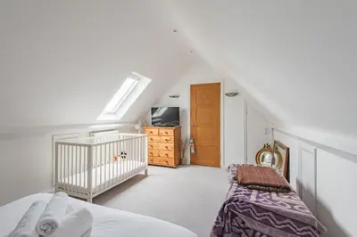 a bedroom with a crib and a room with a tv at St Mary's House by Keepers Cottages in Moffat