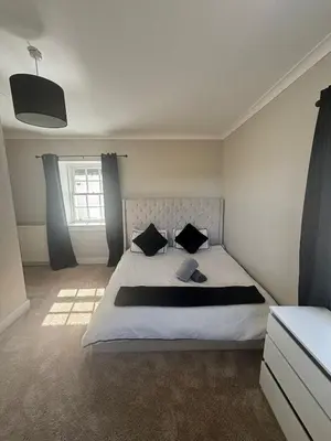 a bedroom with a large white bed with black pillows at Brig o Doon 3 in Ayr