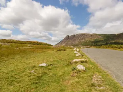 a road in a field next to a mountain at Buckbarrow in Seascale