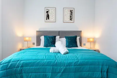 a blue bed in a bedroom with two lamps at The Bay Suite - Donnini Apartments in Troon