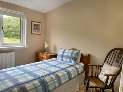 a bedroom with a bed and a chair and a window at Alderneuk Lodge - Uk49923 in Dumfries