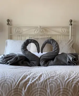 a bed with two snakespretending to be towels at Hollyside Lodge in Carlisle
