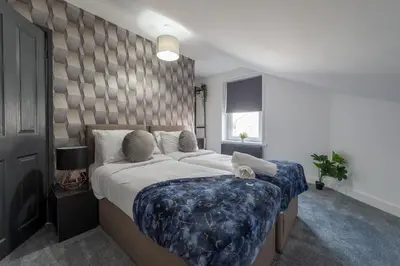a bedroom with a large bed with a blue blanket at 5 Bed Workington House with Parking Near Station in Workington