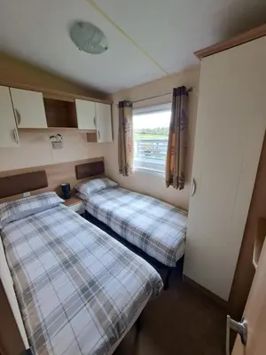a small room with two beds and a window at Three lochs holiday park Loch view 123 in Balminnoch