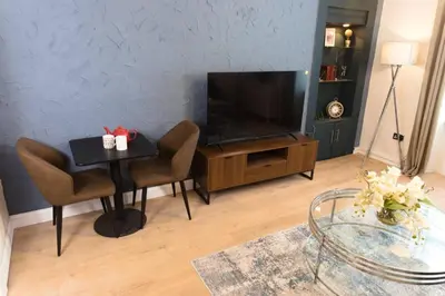 a living room with a table and a flat screen tv at Cosy 1-Bedroom Flat, Walk to Beaches in Troon