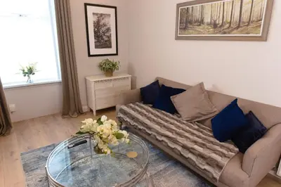 a living room with a couch and a glass table at Cosy 1-Bedroom Flat, Walk to Beaches in Troon