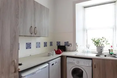 a kitchen with a washing machine and a window at Cosy 1-Bedroom Flat, Walk to Beaches in Troon