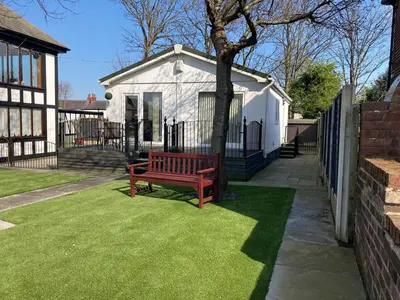 a red bench sitting on the grass in front of a house at Blackpool chalet - free parking in Moffat