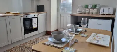 a kitchen with a wooden table with two wine glasses at The Creamery High Harrington in Harrington