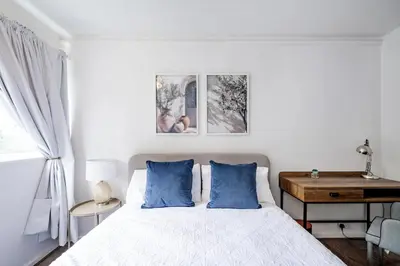 a bedroom with a bed with blue pillows and a desk at Cozy 2 bedroom London Flat in Heart of Pimlico in Moffat