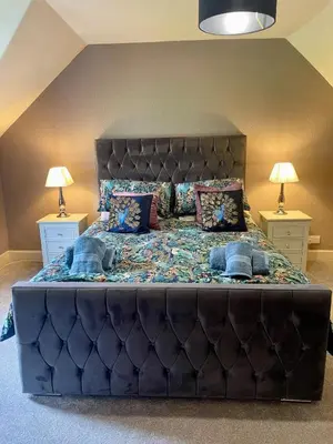a large bed in a bedroom with two night stands at Relax by the River, at Millgreen House in Dumfries